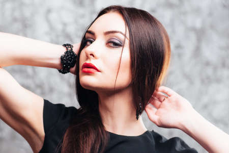 Contrast woman with bright and bold make-up posing against grey background. Brunette with bright make-up posing on camera. Studio shoot of dark hair girl.の写真素材