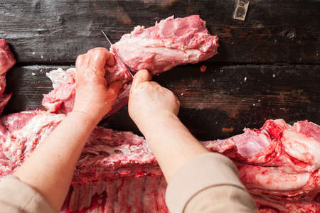 Butcher cuts raw pork chop. Raw pork chop on wooden background. Butcher cuts raw pork chop on cutting table. Top viewの写真素材
