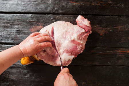 Slicing pork meat on piece in farm market.  Butcher slicing pork meat in local market. Top view on old wooden backgroundの写真素材