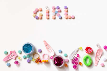 Little girl accessories lifestyle set on  white background.  Many little girl accessories scattered on blank paper - beads, hair clips, eyeshadow. The inscription Girl is on the top of imageの写真素材