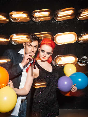 Happy  friends clubbing dancing celebrate concept on dance club background. Woman with  colorful balloon and happy man dance on lights background. Concept of night lifestyle.の写真素材