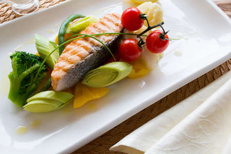Steam salmon with a side dish of fresh vegetables on a white square plate. Top viewの写真素材