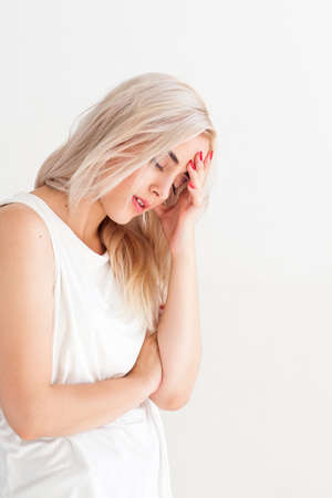 Tired ill woman with headache and flu. Unhealthy sad disappointed girl. Family conflict, illness, crisis, stress, symptom and headache concept. Ill woman on white background with free space.の写真素材