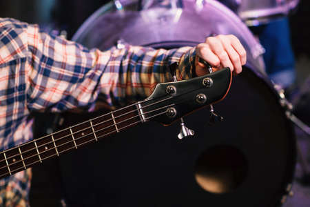 Young man tuning a electric guitar. Selective focus on the hand. Unrecognizable guitarist tuning guitar on concert  stage in sound recording studio.の写真素材