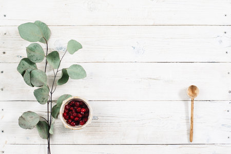 Vegetarian food with free space on wooden table. Red dried fruits and green leaves with top view. Dietary food flat lay on white wooden background with copy space.の写真素材