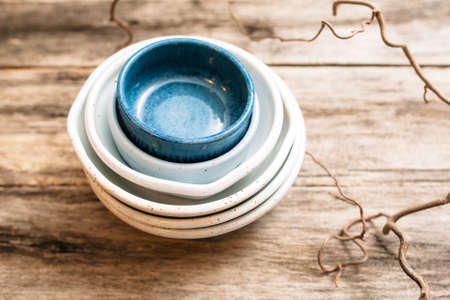 Flat lay set of handmade ceramic crockery. Top view of unusual creative bowls on  old wooden background. Stack of empty ceramic dishes  over wooden table with free space. pottery conceptの写真素材