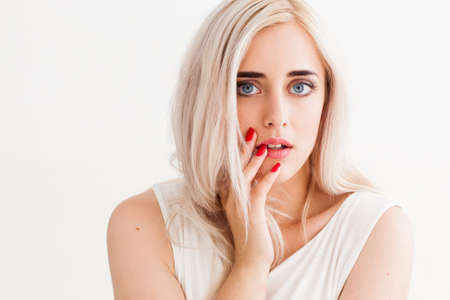 Surprised shoked girl covers her mouth and her eyes wide open. Fashion girl  shows wow on a white background.  Beautiful woman amazed.の写真素材