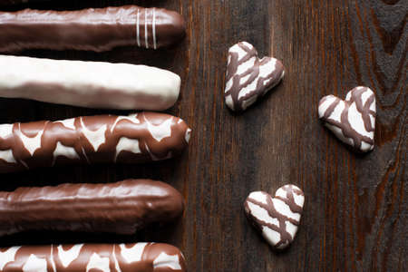 Set of different chocolate cookies, extreme close-up. Sweet chocolate cake sticks and hearts. Flat lay. Composition on dark wooden backgroundの写真素材