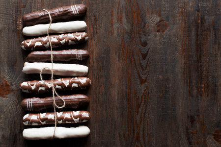Chocolate cake sticks on dark wooden background. Black, white and decorated chocolate cake sticks....