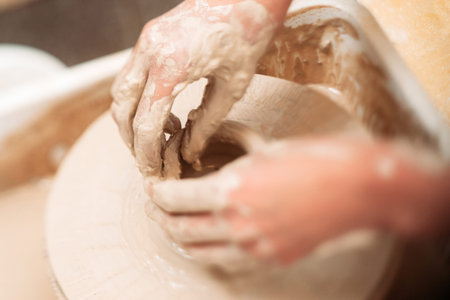 Making ceramics pot dirty hands close-up. Top view on almost ready clay pot and hands, finishing it....