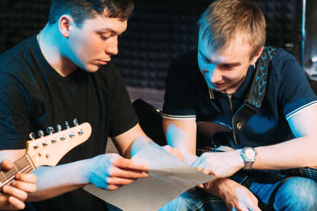 Musicians learn text, explaining moment. Guy explains to the guitar player his party in the song. Guitarist learn new notesの写真素材