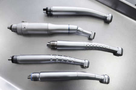 Set of dental turbine handpieces without burs flat lay. Top view on set of dental turbine handpieces on metal medical tray.の写真素材