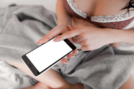 Sexy lady using mobile smart phone. Top view on smartphone with empty screen in female hands. Copyspace on mobile phone screenの写真素材
