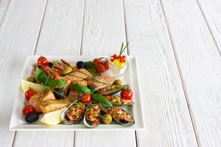 Seafood snack on white wooden background. Closeup of plate with grilled shrimps, salmon and stuffed...