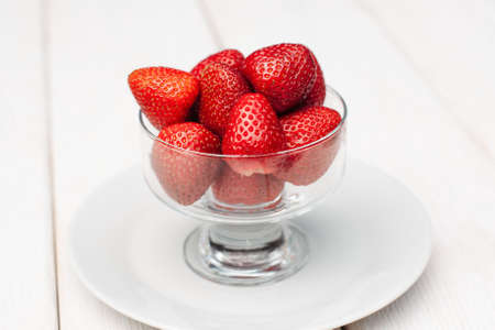 Glass cup with fresh strawberries on white background. Summer snack conceptの写真素材