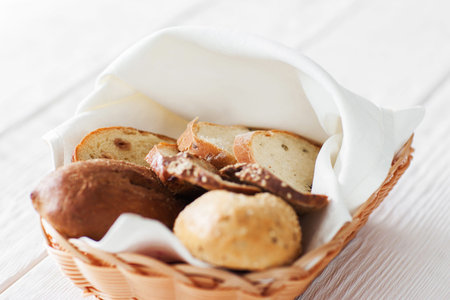 Basket with fresh hot bread on white wooden background, close-up.