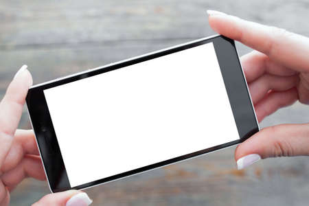 Hand holding mobile phone with white screen on wooden backgroundの写真素材