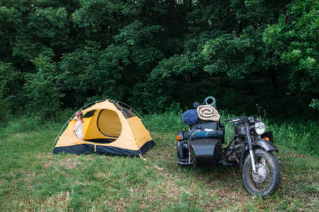 Motorcycle with sidecar parked on green grass next to tent, free space. Camping, activity, rest conceptの写真素材