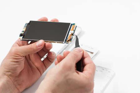 Repairman disassembling smartphone with tweezers.の写真素材