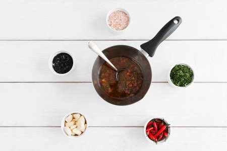 Tasty gravy in pan with spoon on table with variety of ingridients.の写真素材