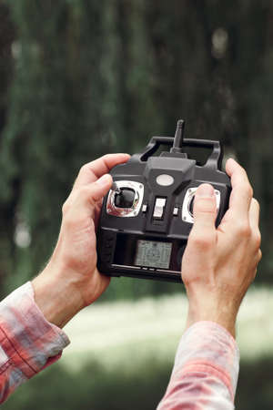 Transmitter for controlling moving device in male hands, blurred nature background.の写真素材