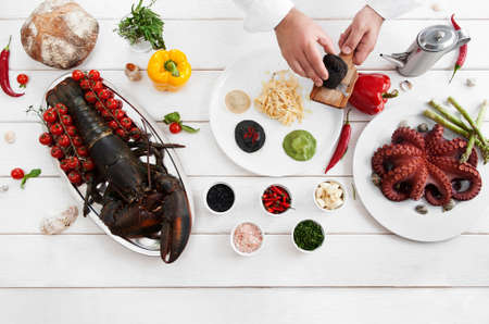 Chef spreading italian traditional meal of pasta and ravioli with black truffle, flat lay, copy space, white wooden background. Italian cuisine, culinary classes, restaurant kitchen conceptの写真素材
