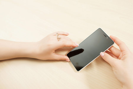 Female hands holding smartphone, customer pov, mockup. Woman using new phone with blank screen,...