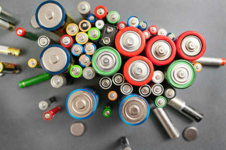 Selection of different batteries, top view on colorful commercial accumulators on gray background. Creative energy composition. Ecology conceptの写真素材