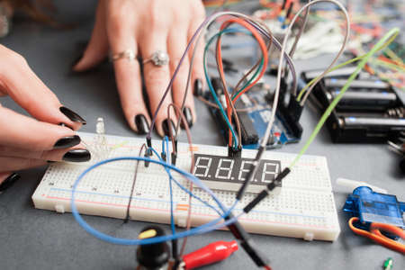 Woman engineer connecting led to breadboard. Electronics development, modern technologies, innovation, hobby conceptの写真素材