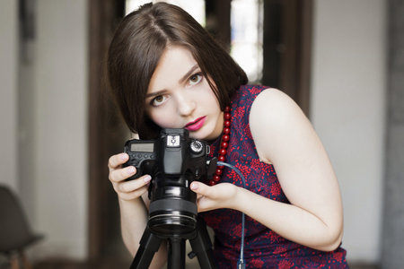 Portrait of beautiful female photographer with camera. Close-up photo of attractive young woman...