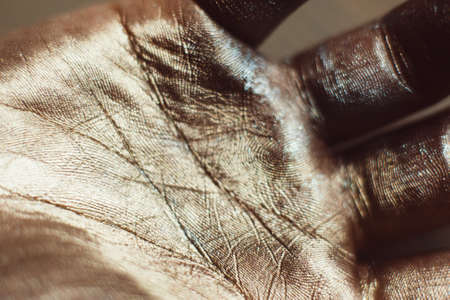 Close-up photo of golden human hand. Patterns on painted palm with gold dust. Luxury design of greasepaint, ceremonial body artの写真素材