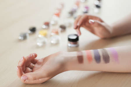 Female hand with eyeshadow colors. Closeup of woman makeup artist testing different eyeshadows, showing swatchesの写真素材