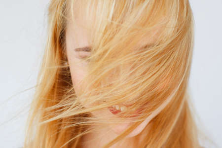 Beautiful healthy red hair close-up. Carroty woman with covered face by locks photo. Head care, beauty, wind, health conceptの写真素材