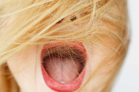 Unrecognizable woman with open mouth and covered face with red hair. Exclaiming carroty girl close-up portrait. Delight, enthusiasm, fun conceptの写真素材
