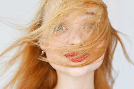 Excited foxy woman portrait, smiling at camera. Jumping girl face, covered with red hair. Fun, happyness, fooling conceptの写真素材