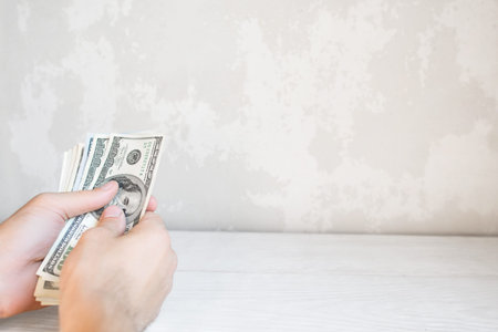 Hand with batch of one hundred dollars, free space. Man counting american money, white background. Currency exchange, profit. win gambling conceptの写真素材