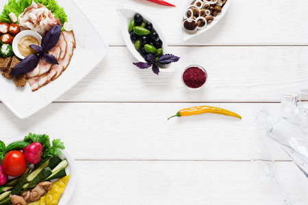 Snacks for vodka, flat lay, copy space. Top view on different tasty meals with glass decanter on...