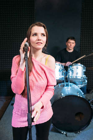 Female singer on stage holding microphone. Woman soloist ready to sing a song, music band performance. Hobby, pastime, show, leisure conceptの写真素材