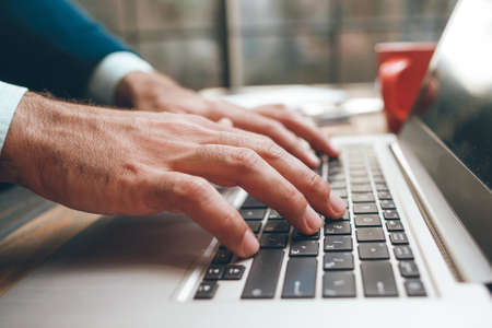 Opened laptop and male hands typing. Fingers on the keyboard. Concept of searching information, chating, communication, virtual relationshipの写真素材