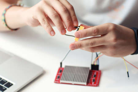Engineer hands connecting electronic components. Close-up of master developing new device, blurred led matrix displayの写真素材