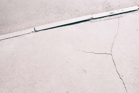 Sidewalk asphalt road with cracks. Old worn and cracked footpath close-up, gray urban backgroundの写真素材