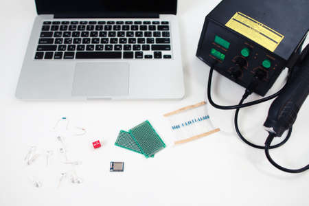 Electronic engineer workplace with components. Top view on laptop, multimeter, breadboard and set of small transmitters. Technology, development, construction conceptの写真素材