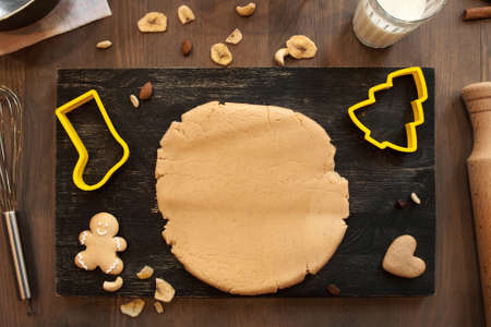 Gingerbread dough with cookies and culinary forms of Santa boot and Christmas tree on kitchen table. Homemade pastry, xmas spirit, winter holidays conceptの写真素材