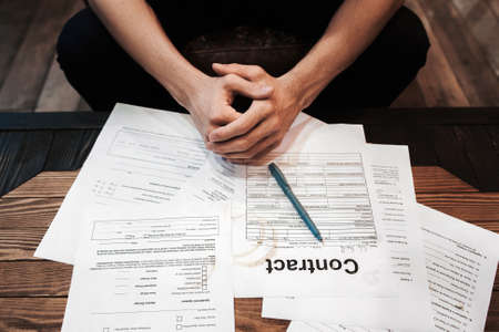 Top view on businessman sitting near lot of documents. Successful entrepreneur workplace. Business,routine, problems, bureaucracy, fortune, new contracts conceptの写真素材