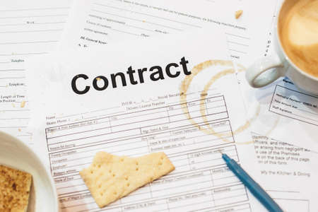 Dirty contract papers with cracker and coffee trace. Close-up of business documents of busy and tired businessman. Mess conceptの写真素材