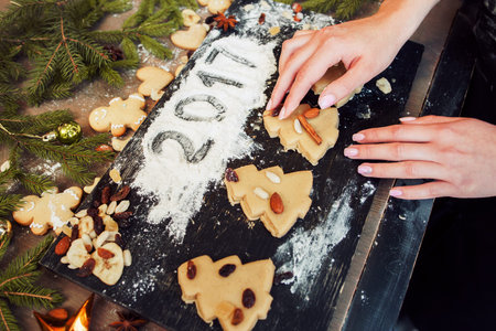 Gingerbread Christmas tree cookies and 2017 sign on flour. Confectioner hands preparing pastry for baking, Christmas treat decorating.の写真素材