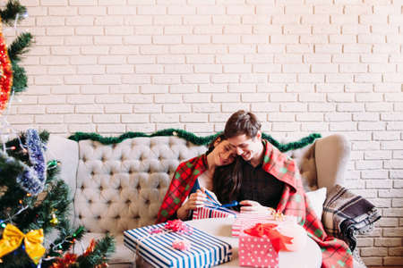 Happy couple sitting near Christmas tree, copy space. X-mas celebration, joy, coziness, love conceptの写真素材