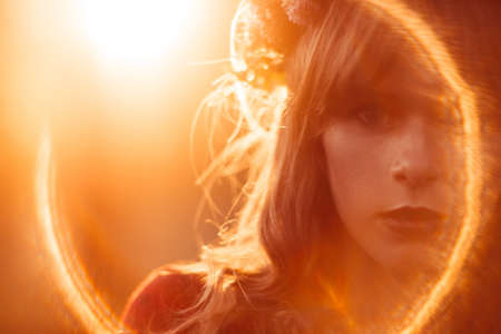 Portrait of beautiful woman, lens flare effect, free space. Close-up of female face, orange light, free spaceの写真素材