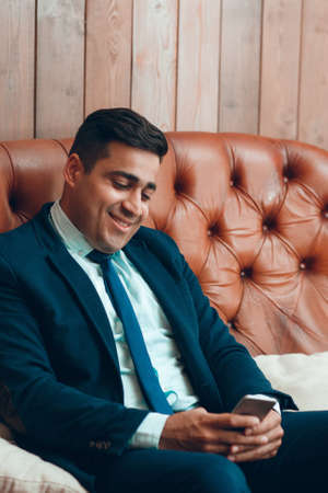 Man browsing the internet on smartphone, copy space. Smiling businessman surfing net on mobile phone. Entertainment and relaxation conceptの写真素材