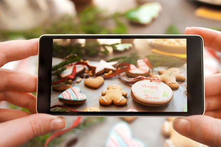 Christmas traditional treat photography on phone. Taking a picture of gingerbread cookies variety. Food photography,   culinary conceptの写真素材